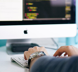 Hands of a man typing in front of a computer